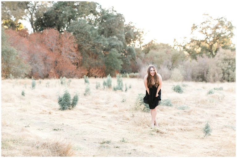 pretty girl in black dress standing in open field
