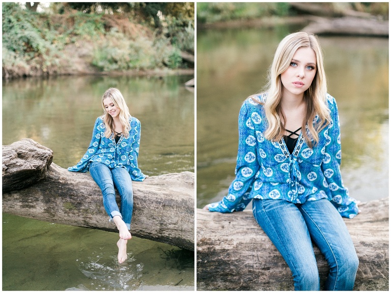 girl in blue shirt and jeans sitting on a log across a river