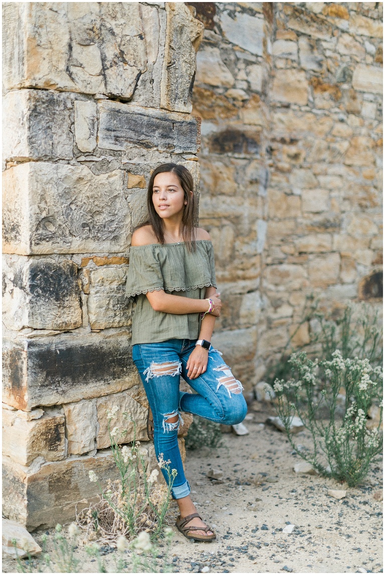 girl leaning against a stone wall