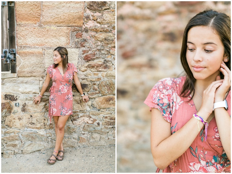 girl in a pink dress standing in front of a stone wall