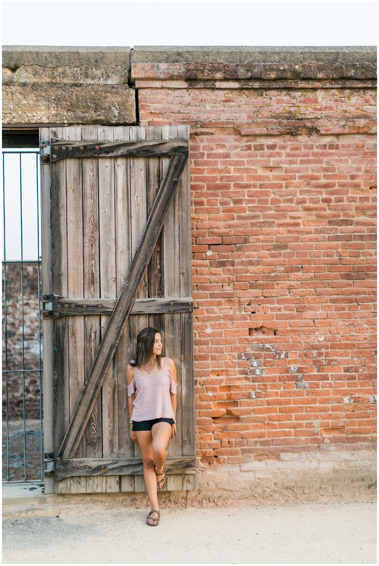 girl leaning against a giant wooden door