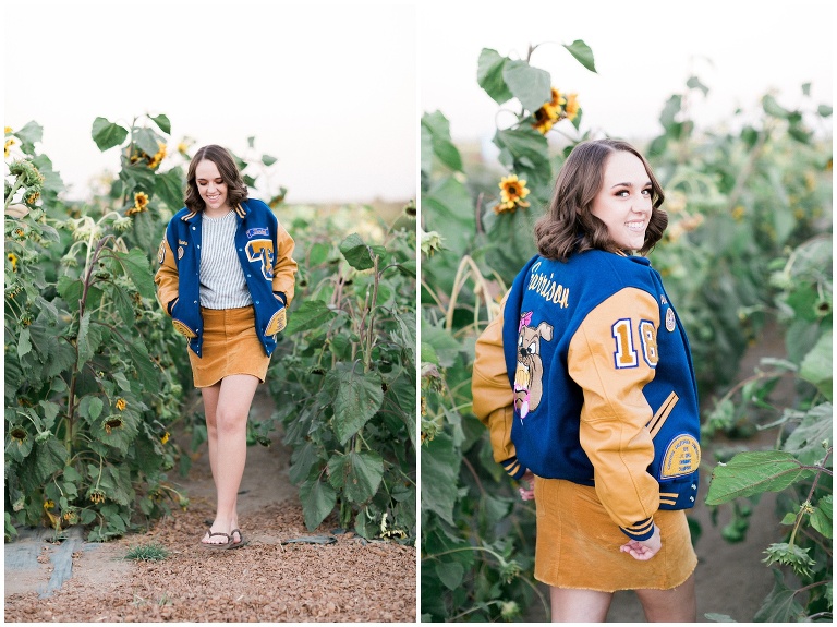 girl in a letterman jacket stand in a sunflower field