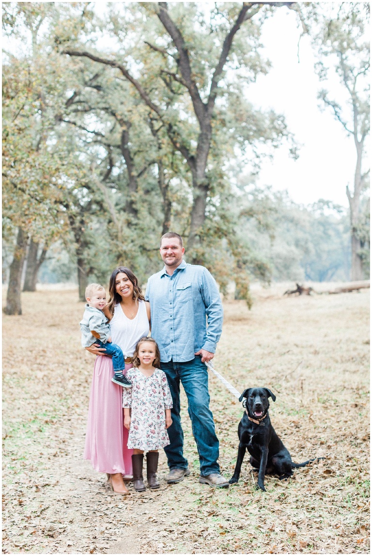 family of four with a black lab dog