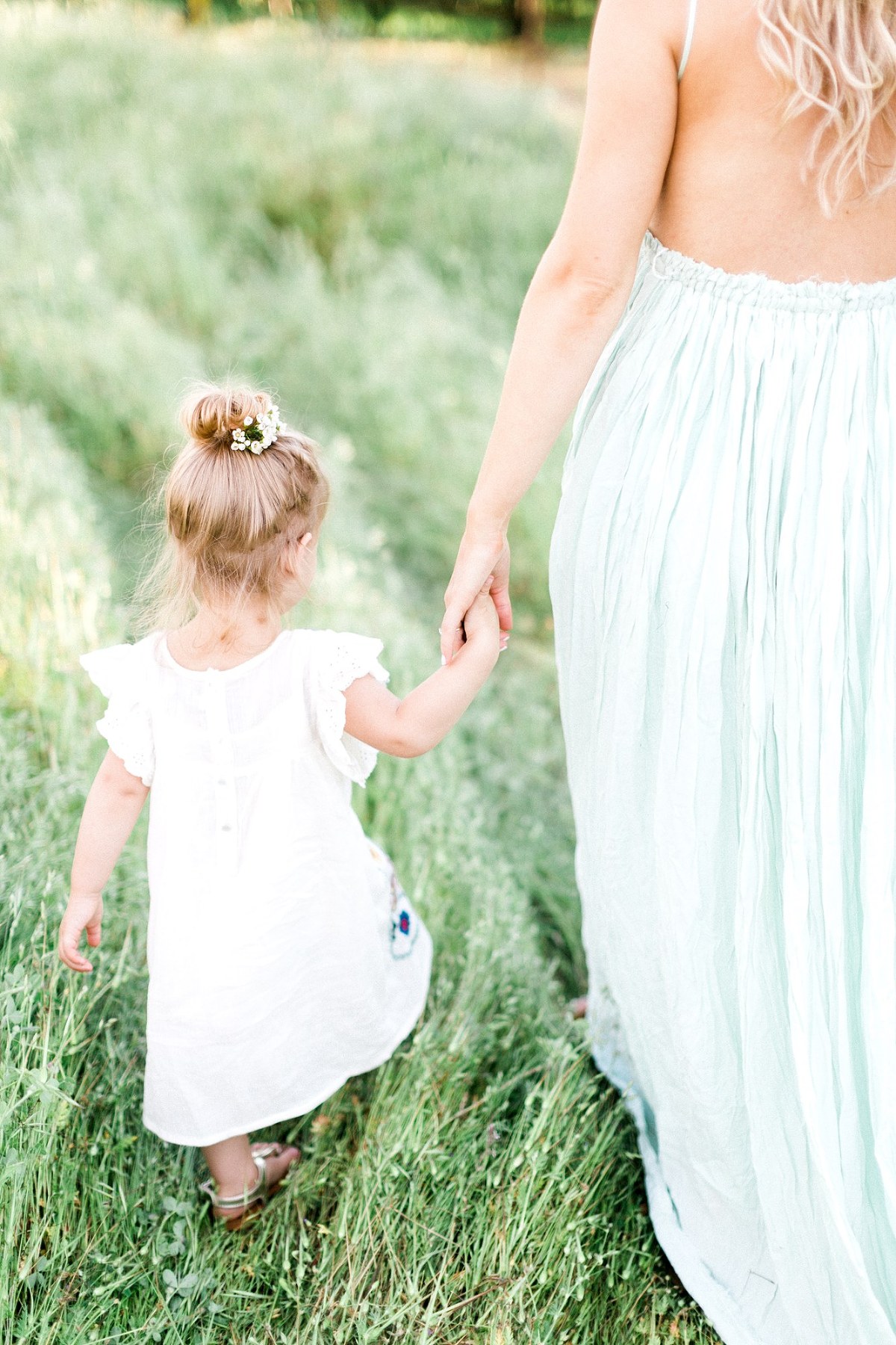 mother and daughter walking through tall grass